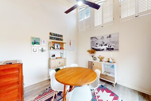 A dining area with a round wooden table, white chairs, a wooden cabinet, and a colorful rug. - Dog-friendly condo with a gas fireplace, washer/dryer, AC, & cable TV (Canyon Lake)