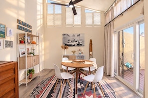 Un coin repas avec une table ronde, des chaises blanches et un tapis à motifs.