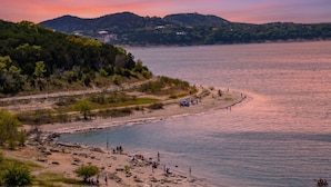 Eine Küstenlandschaft mit Strand, felsigem Ufer und Hügeln im Hintergrund.