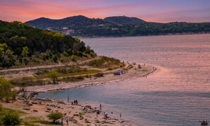 A coastal landscape with a beach, rocky shoreline, and hills in the background. - Cozy 2-Story Condo | 2BR w/ Lake Views | Close to Dinning & Shopping (Canyon Lake)
