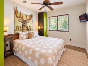 A bedroom with a bed, a ceiling fan, a wall-mounted TV, and a window with blinds. - Newly renovated rustic home with deck by Horseshoe and Tubing (Canyon Lake)