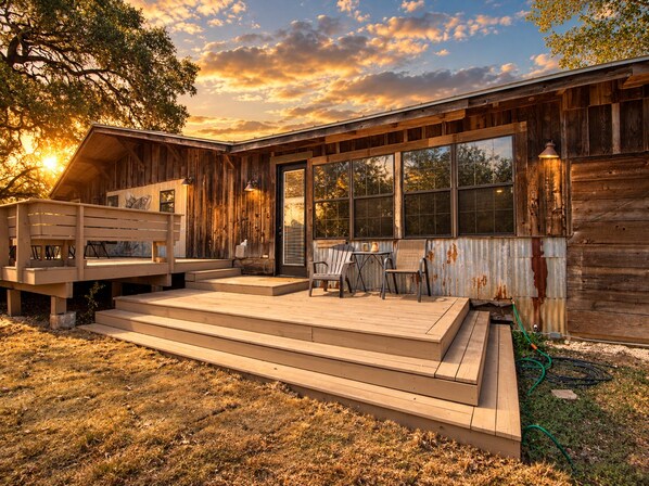 Una cabaña de madera con terraza, ventanas amplias y mobiliario exterior.