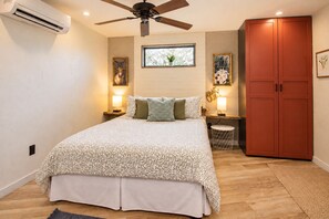 Une chambre à coucher avec un lit, un ventilateur de plafond, une armoire et des œuvres d’art accrochées aux murs.
