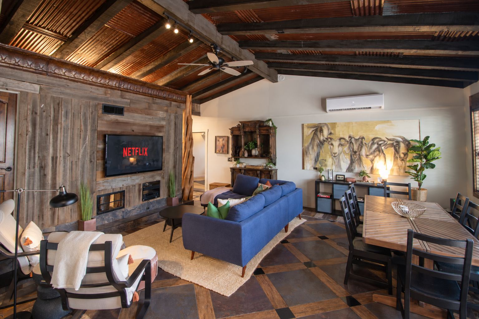 Un soggiorno accogliente con un divano blu, un caminetto, una TV a schermo piatto e un'area pranzo con un tavolo e sedie in legno.