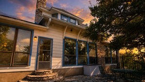 Una casa con escaleras de piedra, ventanas amplias y un patio con mobiliario exterior.