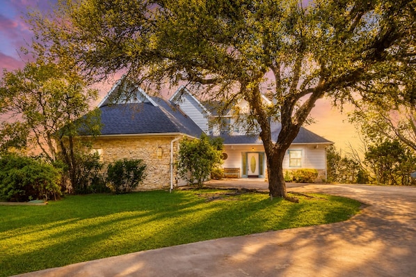 A two-story house with a stone facade, a front porch, and a driveway.
