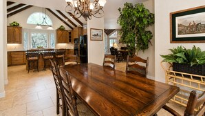 Un'ampia cucina con mobili in legno, un grande tavolo da pranzo e un lampadario.