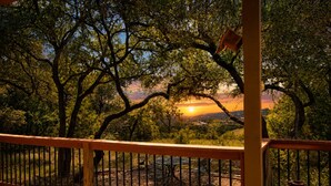 Un balcone con vista su alberi e un tramonto.
