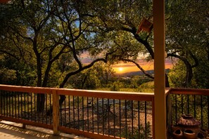 A balcony with a view of trees and a sunset. - 5-acre Hill Country home with views & outdoor entertaining - dog-friendly (Canyon Lake)