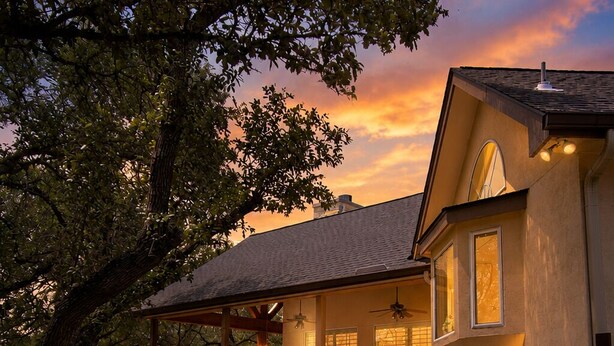 Una casa con veranda coperta, un vialetto che conduce all'ingresso e un giardino curato.