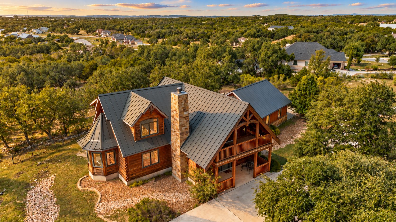 A large, two-story log cabin with a prominent chimney, surrounded by dense greenery and other residential properties.