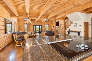 A spacious kitchen with a granite countertop, wooden ceiling beams, and a dining area with a sofa and chairs. - Luxe Lake Living with Bonus Bunk Area & Private Boat Parking - Dogs Welcome (Canyon Lake)