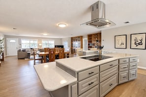 A modern kitchen with a central island, built-in cabinetry, and a dining area with wooden furniture. - Spacious house with living room, kitchen, balcony and Hill country views (Canyon Lake)