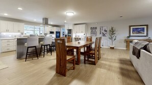 Eine moderne Küche mit weißen Schränken, einem Holztisch und Barhocker.
