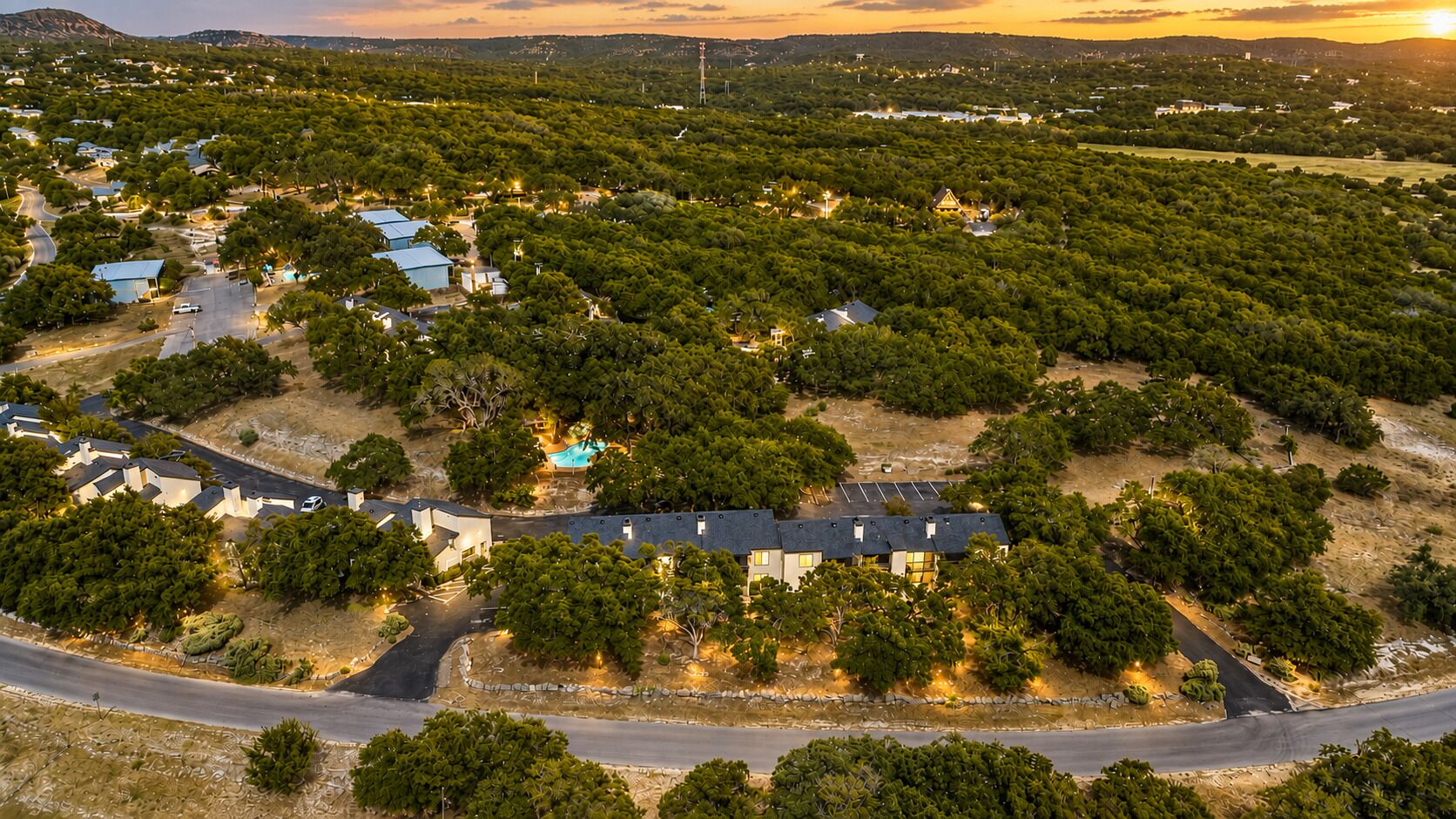 An aerial view of a residential area with houses, a swimming pool, and a road.