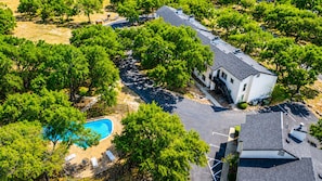 Eine Vogelperspektive auf ein Wohngebiet mit Swimmingpool, Bäumen und einem Haus mit Schrägdach.