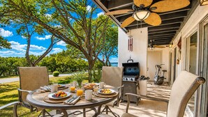 Un patio exterior con una mesa redonda dispuesta para el desayuno, rodeado de sillas, una parrilla y equipo de ejercicio.