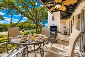 Eine Terrasse im Freien mit einem runden Tisch, gedeckt für ein Frühstück, umgeben von Stühlen, einem Grill und Fitnessgeräten.