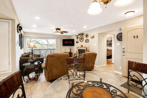 A living room with a fireplace, a television, and a dining area with a round table.