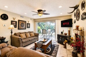 Ein Wohnzimmer mit einer Couch, einem Couchtisch und einem Fernseher, der 'NETFLIX' zeigt.