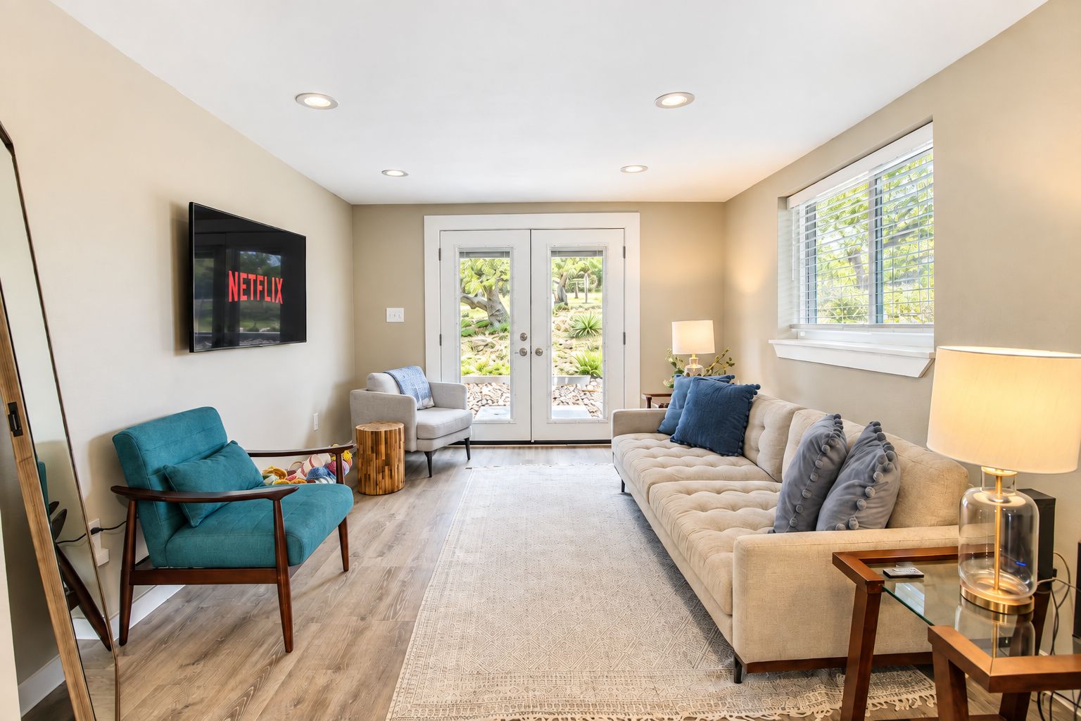 A living room with a sofa, armchair, and a TV mounted on the wall.