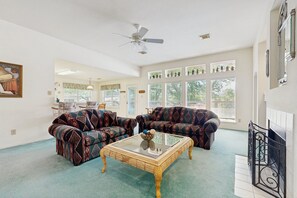 Ein Wohnzimmer mit gestreiften Sofas, einem Glastisch und einem Deckenventilator.