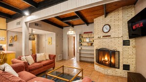 A cozy living room with a fireplace, a sofa set, and a television mounted on the wall. - Funshine | Riverfront house in Mc Queeney with guest house, river views, grill (McQueeney)