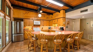 A kitchen with a central island, wooden cabinets, and a stainless steel refrigerator. - Funshine | Riverfront house in Mc Queeney with guest house, river views, grill (McQueeney)