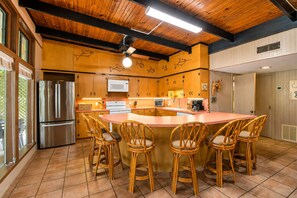 Cocina con una isla central, armarios de madera y un refrigerador de acero inoxidable.