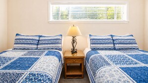A bedroom with two beds, a nightstand, a lamp, and a window with blinds. - Funshine | Riverfront house in Mc Queeney with guest house, river views, grill (McQueeney)