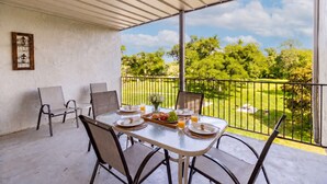 A covered balcony with a table set for breakfast, chairs, and a view of a green landscape. - 3BR | 5 min Drive to Schlitterbahn | Pool, Hot Tub (New Braunfels)