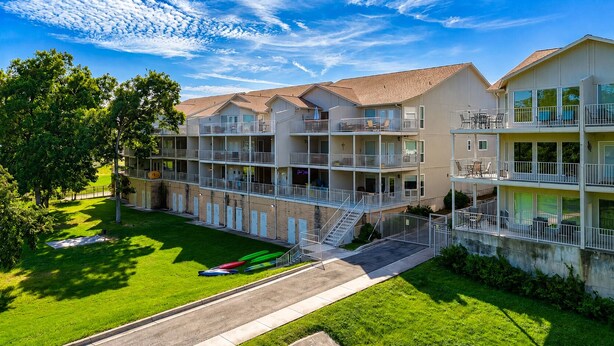 A multi-story hotel with balconies, a grassy courtyard, and a parking area with boats. - 3BR | 5 min Drive to Schlitterbahn | Pool, Hot Tub (New Braunfels)