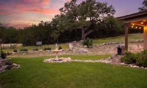 A landscaped garden with a statue, a fountain, and a barbecue area. - Steps to Remi's Ridge & Hayes Hollow Century Oak Casita - Near Canyon Lake (Spring Branch)