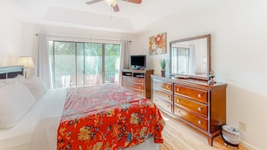 Ein Schlafzimmer mit Bett, Schminktisch, Fernseher und Deckenventilator.