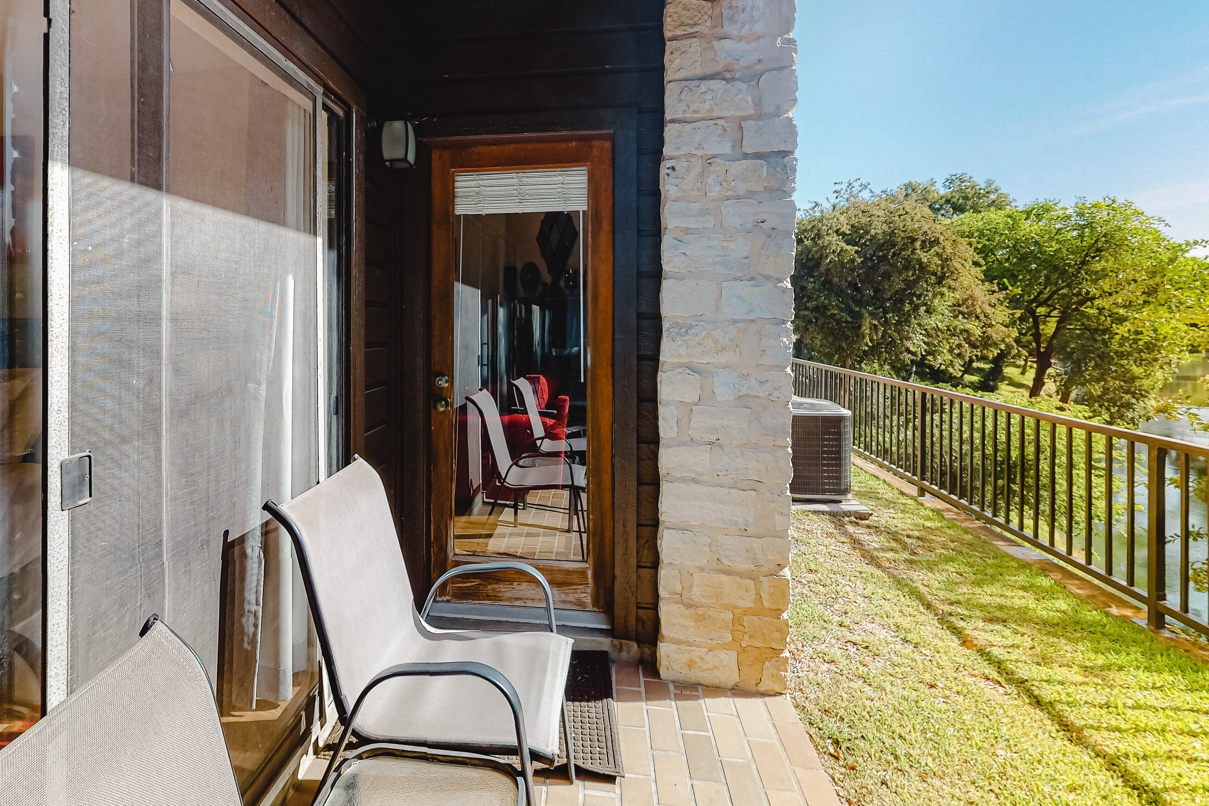 A balcony with outdoor seating, a stone wall, and a view of a lake.