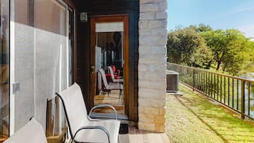 A balcony with outdoor seating, a stone wall, and a view of a lake.