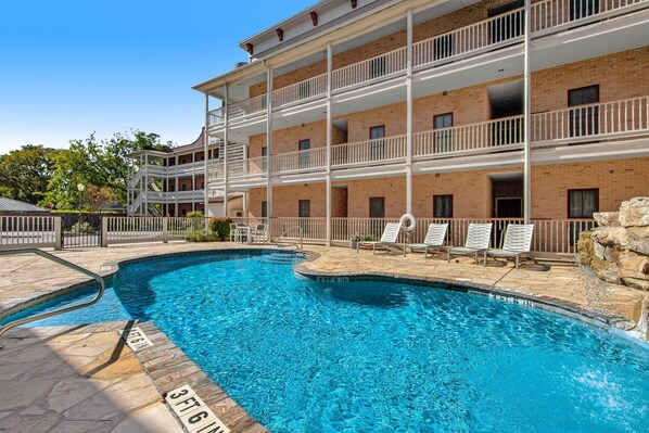 A multi-story building with a swimming pool. - 3BR Riverfront Condo | Balcony | Pool | W/D | Snowbirds Welcome (New Braunfels)