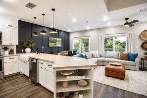 A modern kitchen with a central island, white cabinetry, and pendant lighting.
