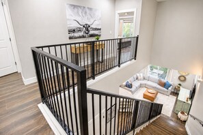 A multi-level living space with a staircase, a sofa set, and a dining area.