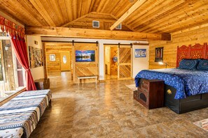 L'intérieur d'une cabane en bois, avec un lit, un banc et des œuvres d'art accrochées aux murs.