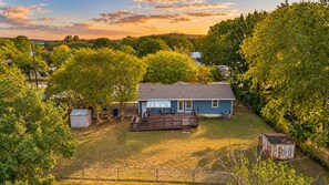 A residential property with a house, a fenced yard, and surrounding trees. - Fully updated home with deck, gorgeous views, about 30 minutes from downtown (New Braunfels)