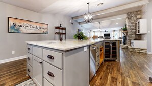 Una cocina amplia con una isla grande, suelo de madera y una pared decorativa de piedra.