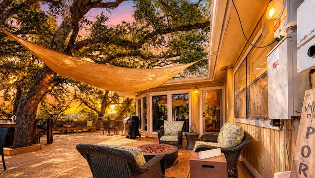 Una terraza de madera con muebles de mimbre, un pozo de fuego y una pérgola.
