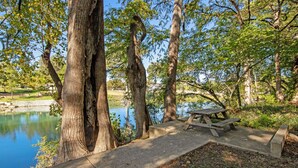Ein Picknicktisch am See, umgeben von großen Bäumen.
