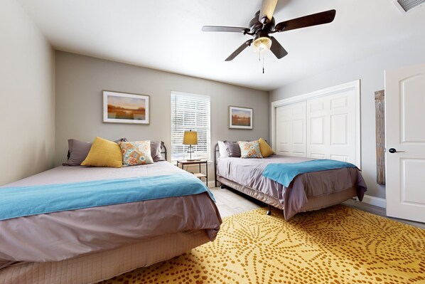 Une chambre avec deux lits, un ventilateur de plafond et un tapis à motifs.