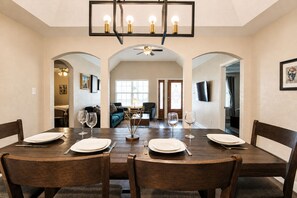 A dining area with a wooden table set for four, flanked by two archways leading to a living room. - Cozy 3BR 5min Walk 2 Alamodome | Close to Downtown (San Antonio)