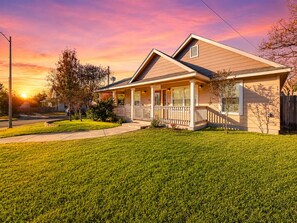 A single-story house with a front porch, a driveway, and a well-maintained lawn. - Welcoming home walkable to Steps of Alamodome & riverfront & near River Walk (San Antonio)