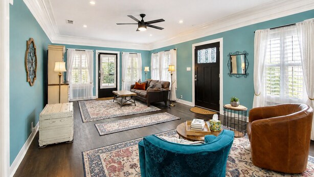 A spacious living room with a sofa, a coffee table, a blue armchair, and a ceiling fan.