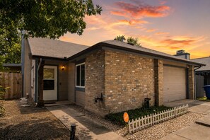 A single-story brick house with a garage, a front door, and a small porch. - Cozy Home | Pool Table & 2 Arcade Games | Enclosed Backyard (San Antonio)