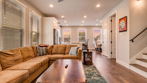 A living room with a sectional sofa, a wooden coffee table, and a dining area with chairs and a table.